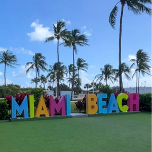 Miami Beach sign at Lummus Park, with palm trees in the background.